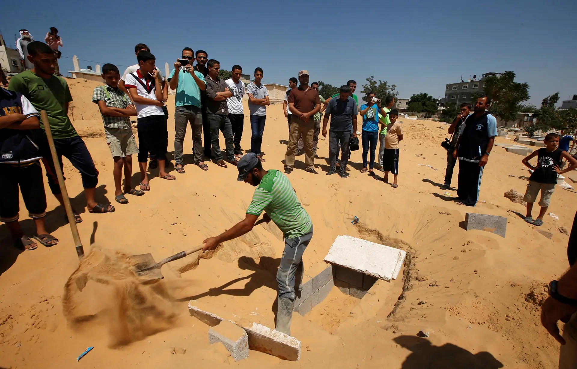 Palestinian prepares a grave to bury the bodies