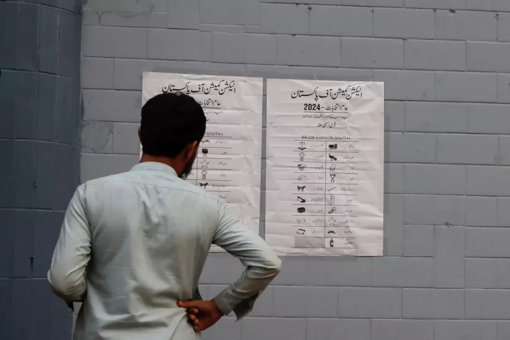 man looks at the poster with the names of contesting candidates and their electoral signs outside a polling office set up for general election in Karachi Pakistan