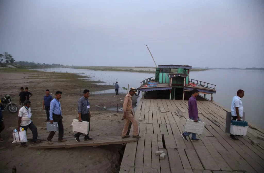 Election officers carry Electronic Voting Machines (EVM) on board a ferry to cross the Sowansiri river to reach a polling center on the eve OF elections in Majuli, India, March 26, 2021. (AP Photo/Anupam Nath, File)