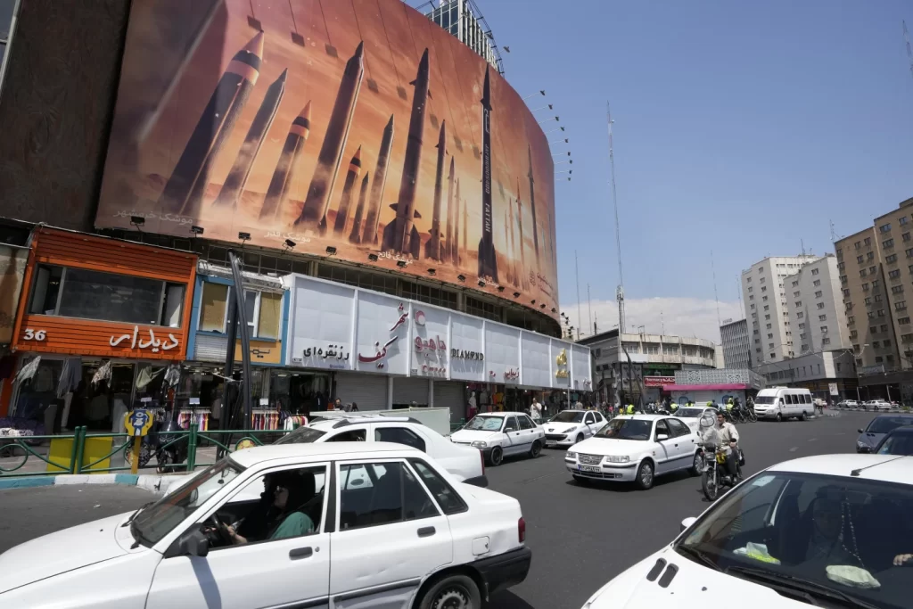 Vehicles drive past an anti Israeli banner showing missiles being launched in a square in downtown Tehran Iran