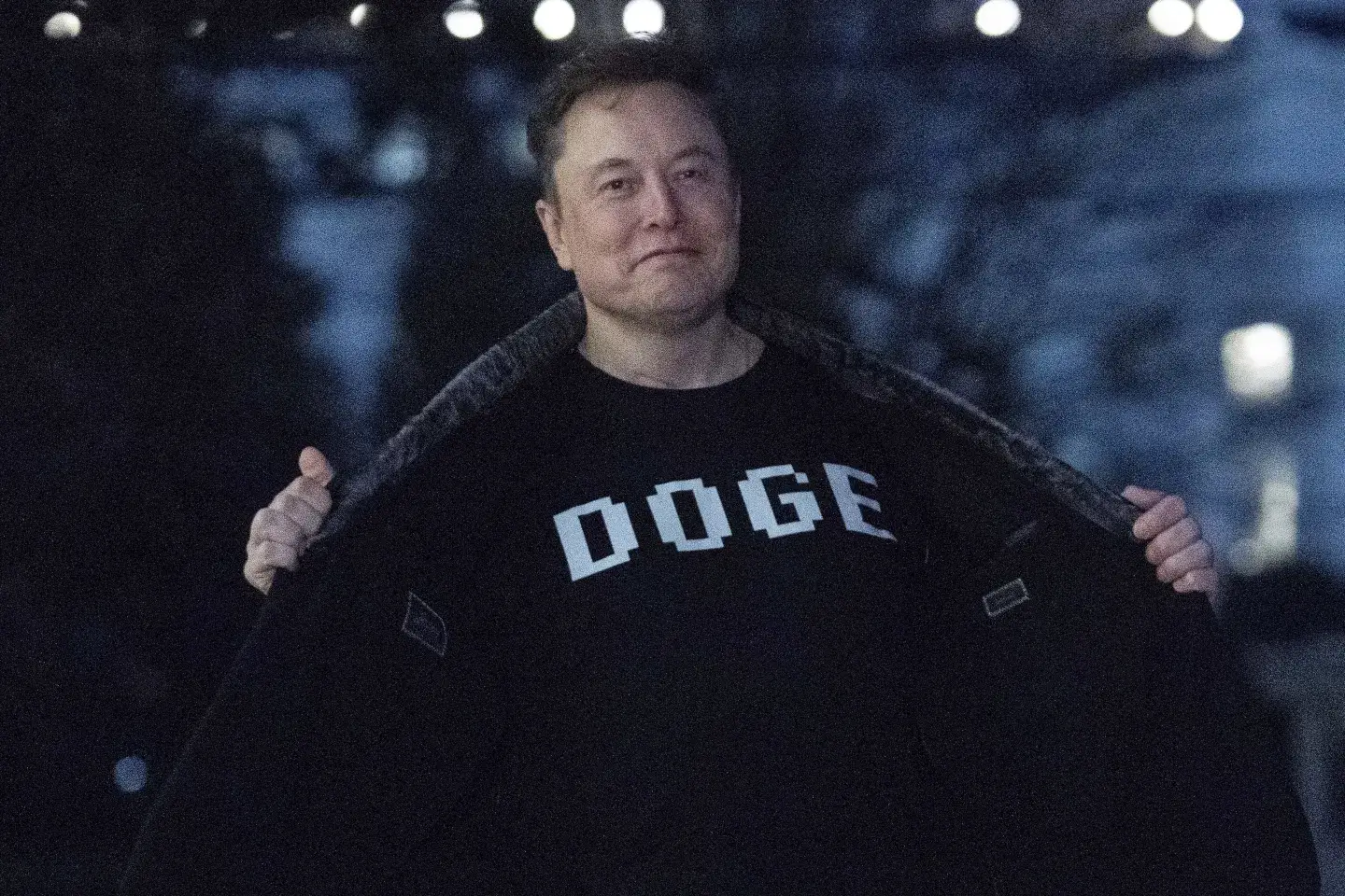 Elon Musk flashes his T-shirt that reads “DOGE” to the media as he walks on the South Lawn of the White House, in Washington, March 9, 2025.