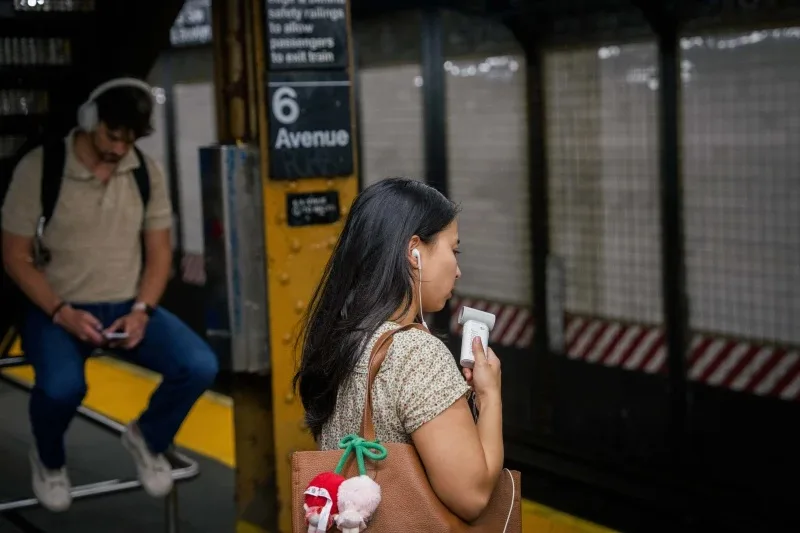 How to stay safe while traveling during extreme heat 1 person uses a mini electric fan