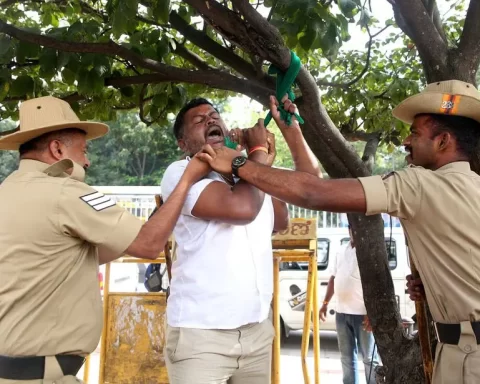 Police officers intervene as a man attempts to hang himself during a protest to oppose the sharing of river water with a neighboring state, in Bengaluru, India, September 26, 2023. REUTERS/Stringer