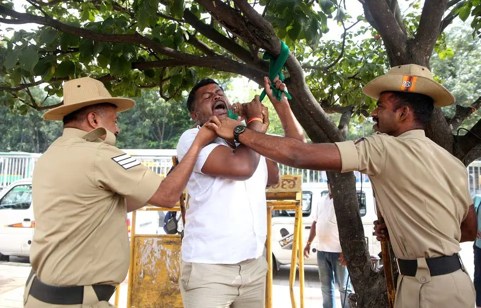 Police officers intervene as a man attempts to hang himself during a protest to oppose the sharing of river water with a neighboring state, in Bengaluru, India, September 26, 2023. REUTERS/Stringer